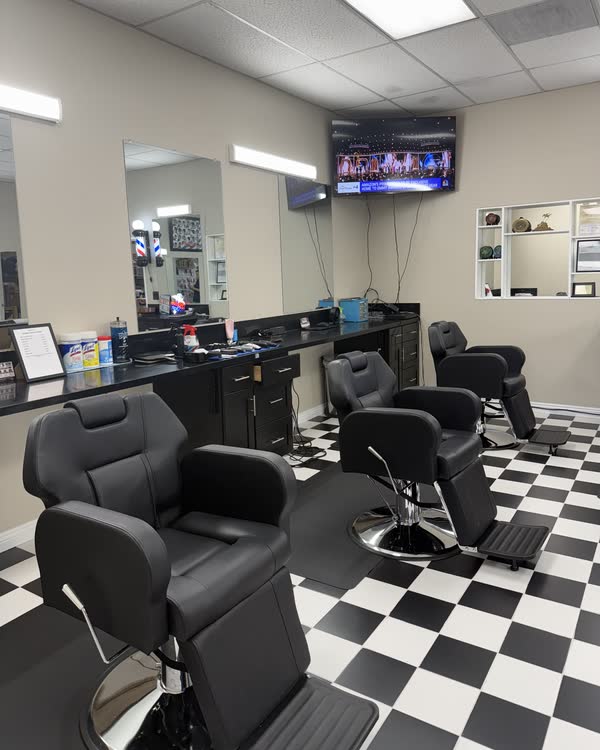 The row of barber chairs, mirrors and the TV inside the shop