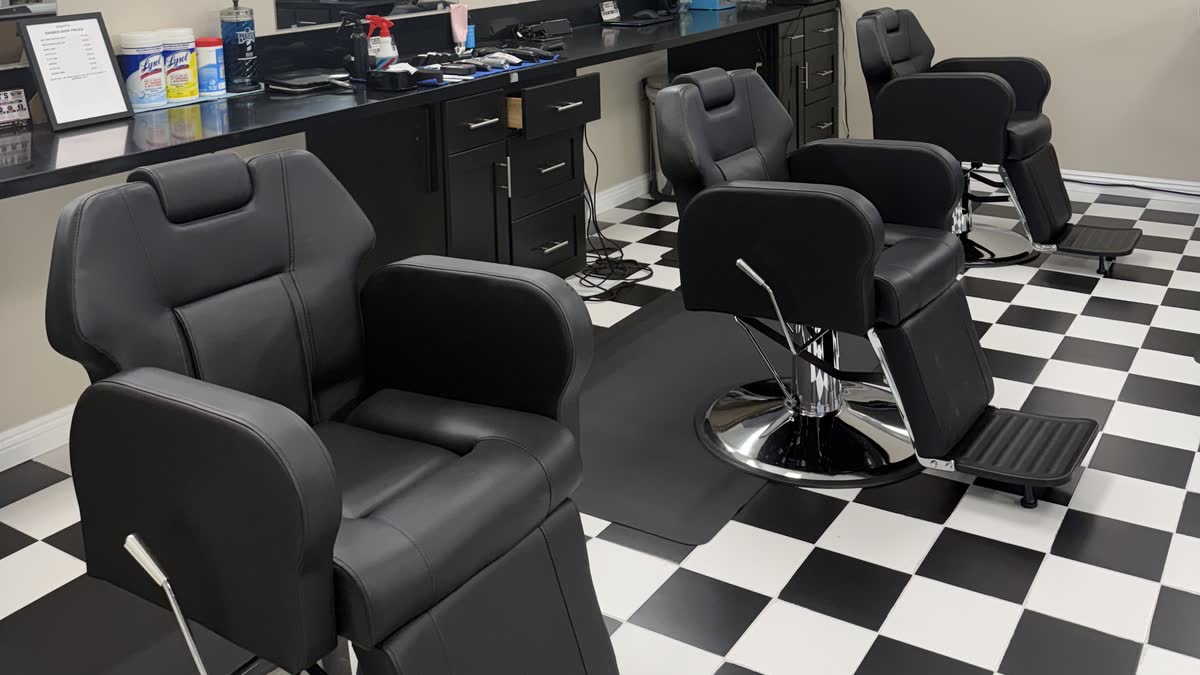 Three black barber chairs in a row on the black-and-white checkered floor