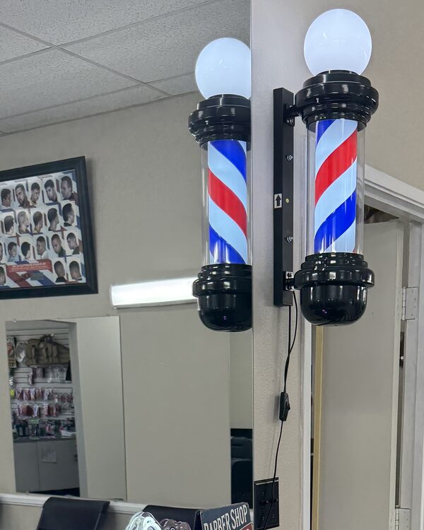 Two lit barber pole lamps on the wall by the mirror